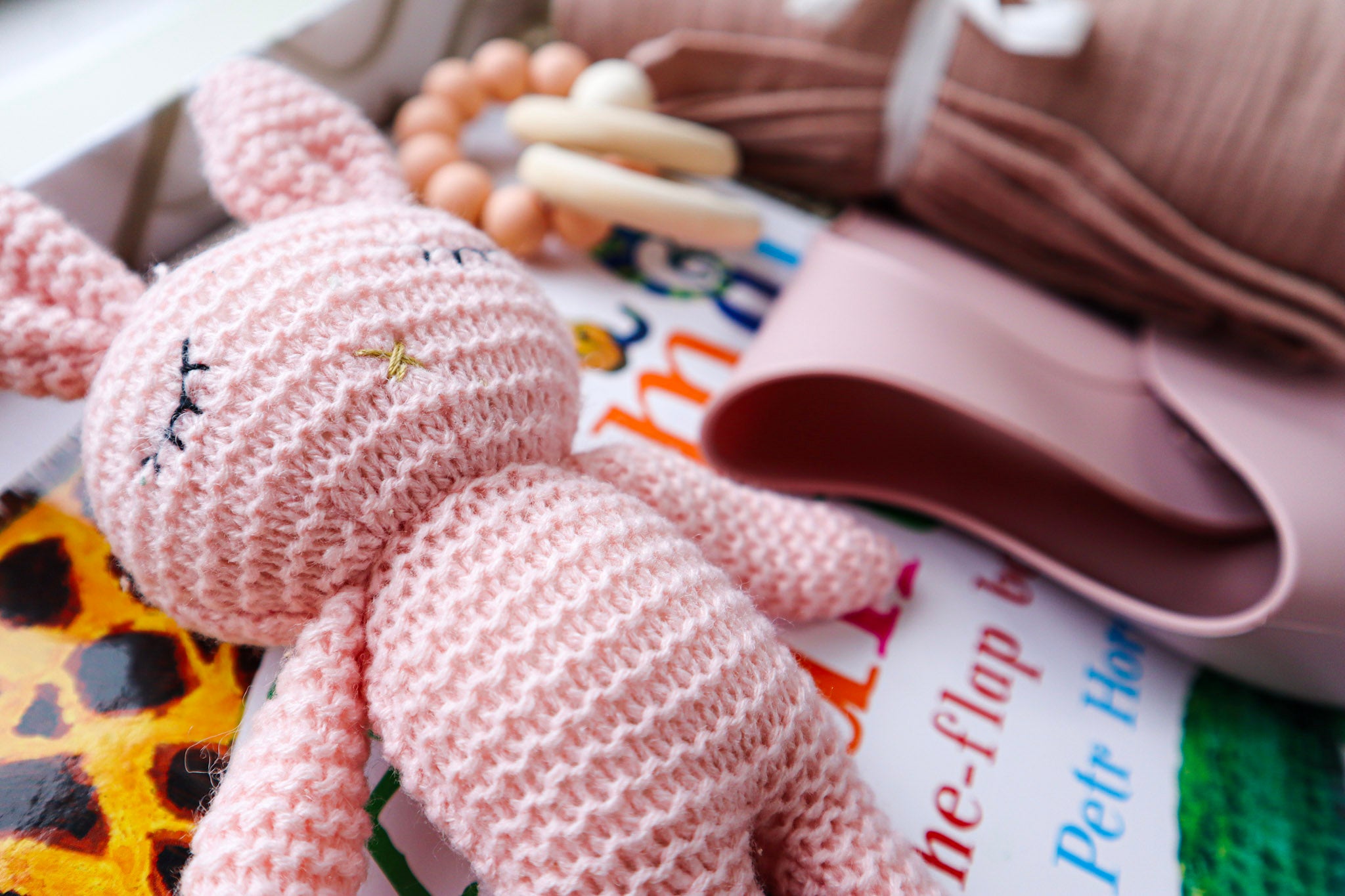 A soft pink crocheted, sleeping bunny toy lying on a children's hardcover book titled Animal Counting