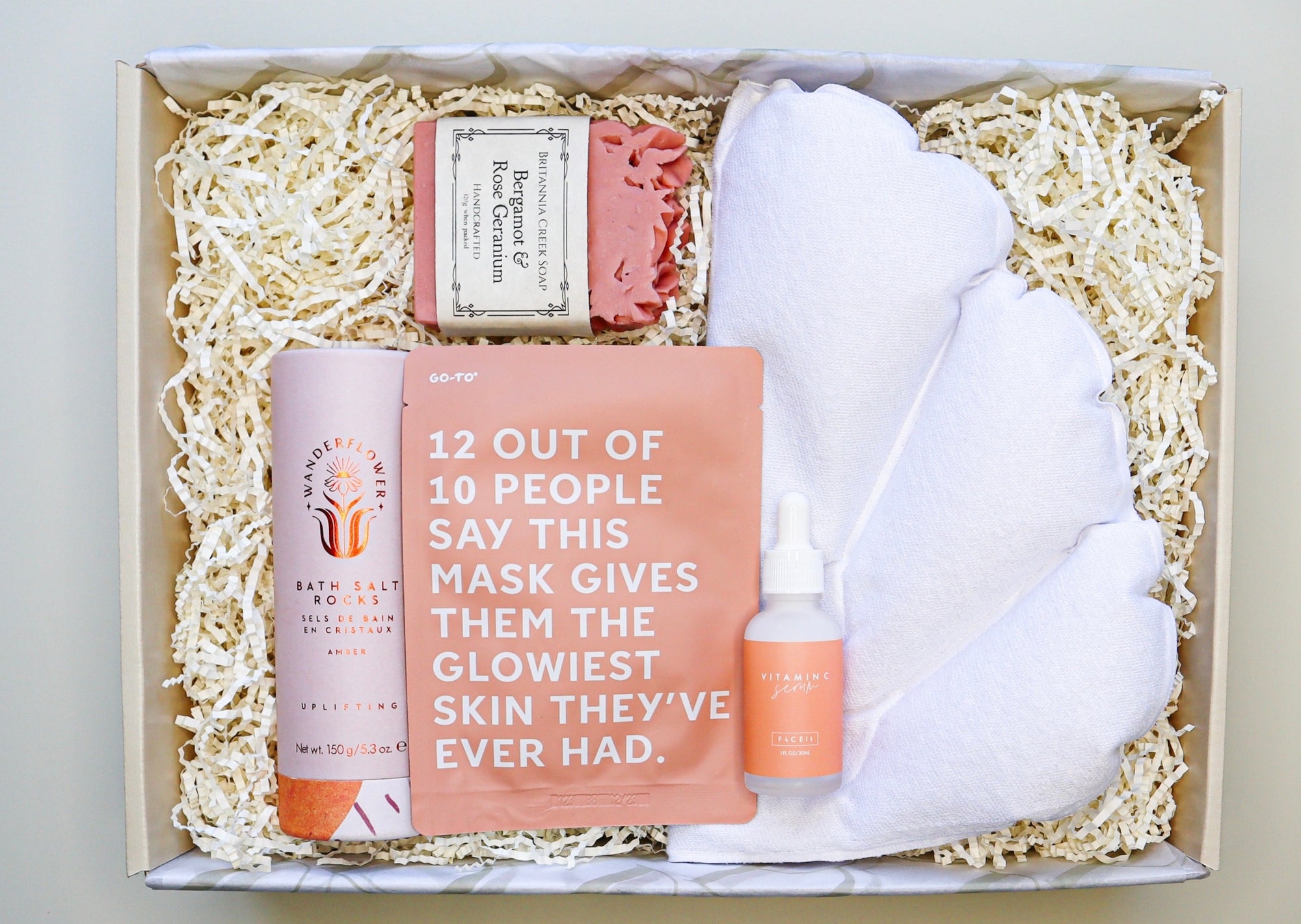 Bath Time Gift Box is a cream box filled with Wanderflower Bath Salt Rocks, Brittania Creek Bergamot & Rose Geranium Soap, a Go-To Face Mask, Face It Vitamin C Serum and a shell shaped inflatable bath pillow