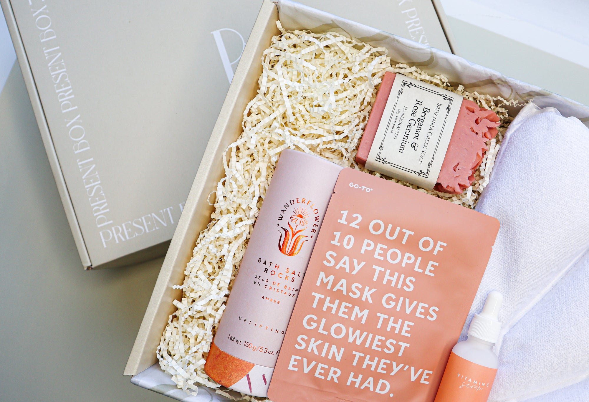 Bath Time Gift Box is a cream box filled with Wanderflower Bath Salt Rocks, Brittania Creek Bergamot & Rose Geranium Soap, a Go-To Face Mask, Face It Vitamin C Serum and a shell shaped inflatable bath pillow