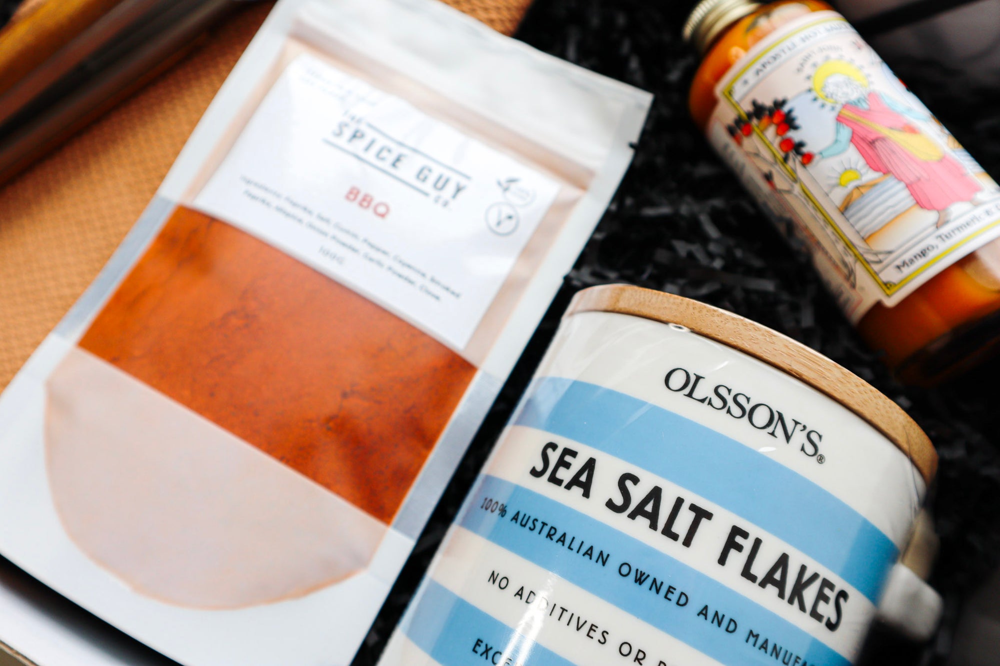 Close up of Olsson's Sea Salt Flakes, Spice Guy Co BBQ Spice Mix and Apostle Hot Sauce Bottle