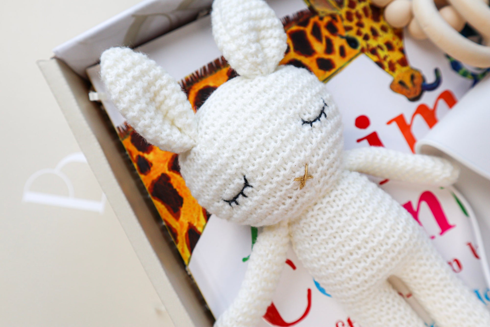 Close up of a white crocheted sleeping bunny toy, lying on top of a child's hardcover book titled Animal Counting